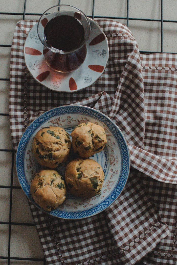 Warm tea served with freshly baked muffins on a rustic checkered cloth background.