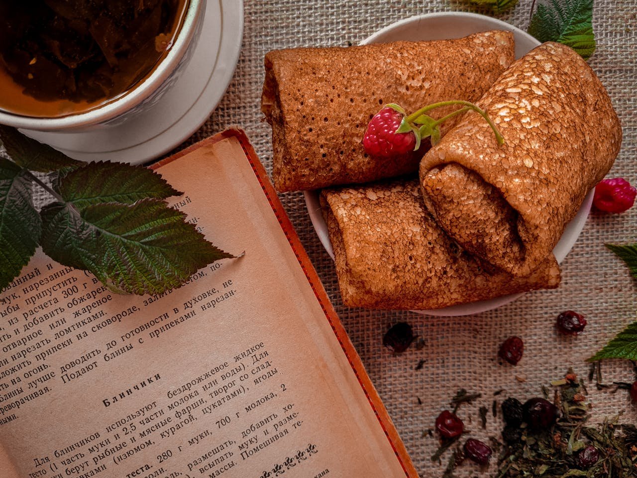 Delicious rustic breakfast scene with pancakes, tea, and a vintage cookbook for cozy mornings.